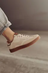 Zapatillas bajas de cuero color marrón con suela de goma color caramelo y cordones marrones.