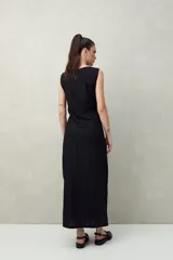 Vestido largo negro de punto con textura acanalada, corte recto y aberturas laterales.