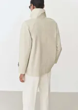 Anorak color beige con cuello de pico con solapa, manga larga con trabillas, cierre de doble botonadura y dos bolsillos laterales.