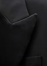 Blazer negro con solapas satinadas, forro interior y cierre de un botón.
