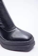 Botas bucaneras negras con plataforma y taco, diseñadas para un ajuste ceñido hasta la rodilla.