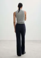 Pantalón de vestir azul marino con finas rayas verticales blancas, corte recto, tiro medio, lazo a la cintura y cierre de gancho y cremallera.