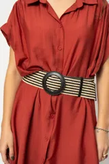 Cinturón tejido con patrón de rayas horizontales en tonos beige y negro. Hebilla circular grande de color negro.