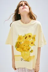 Remera color crema de corte amplio con estampado de girasoles en un jarrón y la firma 'Vincent'.