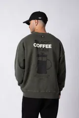Buzo marrón de algodón rústico con lavado gastado y cuello redondo. Estampa frontal con la frase "Coffee Break". Corte oversize.
