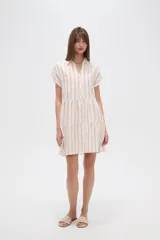 Vestido corto con cuello camisero, de corte holgado y mangas cortas. Presenta un diseño a rayas verticales en tonos beige y blanco, con volados en la falda y cierre frontal con botones.