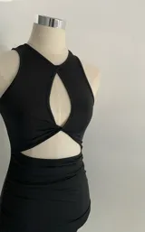 Minivestido negro ajustado al cuerpo, con escote halter con abertura en forma de gota y falda drapeada.