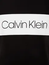 Remera de manga corta Calvin Klein color negro con banda horizontal blanca en el pecho y logo de la marca en color negro sobre la banda blanca.