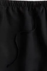 Short negro de corte holgado, con cintura elástica ajustable con cordón y bolsillos laterales.