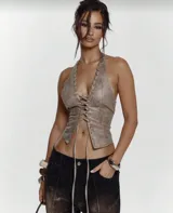 Top color beige con textura símil cuero, corte ajustado, escote halter con cordones cruzados y espalda descubierta.