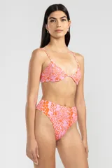 Conjunto de bikini de dos piezas con estampado de flores y caritas sonrientes en tonos rosados y naranjas. El corpiño es triangular con breteles finos y la bombacha es de tiro alto con cobertura mínima.