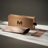 Lentes de sol con montura rectangular de bordes redondeados en color negro y cristales polarizados de color marrón. Presentan un diseño de perfil fino con el logo dorado de la marca Meller en las patillas y ofrecen protección UV400.