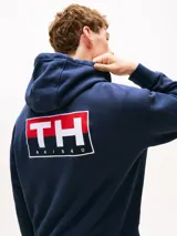 Buzo azul marino amplio con capucha y cordón distintivo, bolsillo canguro, puños y bajo de punto canalé, logo oversize de Tommy Hilfiger en la manga y la parte trasera, parche con logo de Tommy Hilfiger en el pecho y detalles distintivos de Hilfiger Sailing.