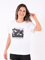 Remera blanca de manga corta con estampa rectangular de palmeras y texto "CREATE NEW HORIZONS FEELING THE BREEZE OVER YOUR SKIN".