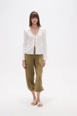 Blusa blanca de algodón con textura fruncida, manga larga y escote en V con lazo ajustable en el centro del busto.