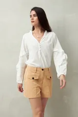 Short blanco de tiro alto con bolsillos delanteros con solapa y botones a la vista.