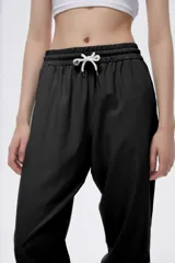 Pantalón de jogging color celeste con cintura elástica ajustable con cordón y puños elásticos. Presenta tres tiras verticales blancas en la parte inferior de la pierna.