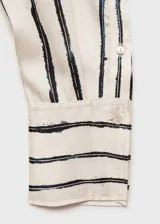 Blusa de poliéster color blanco con estampado de rayas verticales negras, escote cruzado en V y mangas largas con puños abotonados.