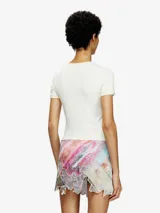 Remera ajustada de manga corta, color blanco hueso, con cuello redondo. Presenta un estampado central de un corazón rojo con el logo de Diesel en su interior.