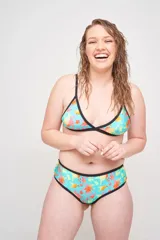 Conjunto de bikini con corpiño triangular con tirantes finos y bombacha clásica, ambos con estampado animal print multicolor y ribetes negros.