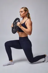 Top deportivo color beige con banda inferior azul y tirantes finos azul marino. Espalda cruzada con doble tira.