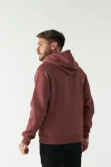 Campera de felpa color bordó con capucha y cordón ajustable, cierre frontal con cremallera, bolsillos laterales y logo estampado en el pecho.