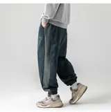 Pantalón de estilo babucha/jogging, color azul oscuro, confeccionado en tela tipo gamuza suave. Presenta una guarda lateral blanca y cintura elástica con cordón regulable. Cuenta con tres bolsillos: dos delanteros y uno trasero.