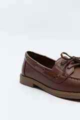 Zapato náutico color beige, de símil cuero, con cordones y suela marrón antideslizante.
