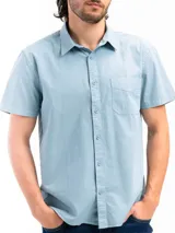 Camisa de manga corta color beige, confeccionada en 100% algodón, con cuello clásico, cierre frontal con botones y bolsillo en el pecho.