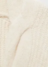 Sweater color crema de tejido de punto grueso con diseño trenzado, cuello en V y corte recto.