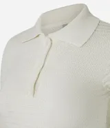 Blusa de punto color crema, con cuello polo, mangas cortas y puños con botones.