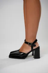 Sandalias de charol negro con correa al tobillo y hebilla plateada, punta fina y tacón bloque.