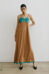 Vestido largo color marrón de gamuza con breteles finos, escote redondo, bordado floral turquesa en el escote y galón turquesa en el ruedo.