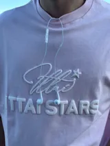 Remera celeste de corte holgado con cuello redondo y estampado en relieve con el logo de la marca y la frase "Ittai Stars".