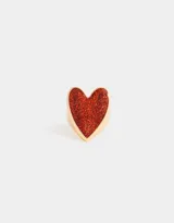 Anillo dorado con forma de corazón rojo brillante.