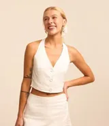 Blusa chaleco color blanco, con frente única, lazo en el cuello, lastex en la espalda y botones delanteros.