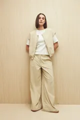 Pantalón color beige de corte ancho y tiro alto, con bolsillos delanteros amplios.