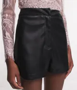 Short negro de cuero sintético con cintura alta, cierre frontal con botón y cremallera, y pinzas en la parte trasera.