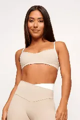 Top deportivo color beige con tirantes finos blancos, forro interno y diseño minimalista.