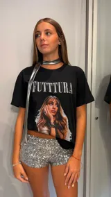 Remera negra de corte oversize con estampado frontal que incluye la palabra "FUTTTURA" en blanco y una imagen de una mujer de cabello largo y castaño.
