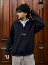 Buzo negro de felpa con frisa gruesa, corte boxy, medio cierre y estampado minimalista.