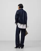 Campera bomber de denim de algodón color azul oscuro, con cuello solapa, manga larga con puño ancho, botonadura frontal, bolsillos con solapa y botón en el pecho, canesú en la espalda y bajo elástico redondeado.