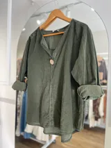 Blusa verde militar de pana fina con cuello en V y manga larga con puños arremangados.