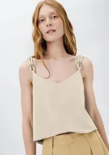 Musculosa color beige con escote en V y tirantes anchos ajustables con hebillas metálicas.