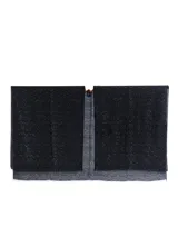 Capa o poncho de tejido de punto negro con patrón de zigzag y detalles brillantes o lentejuelas incrustadas. Presenta un escote en V cruzado y bordes deshilachados.