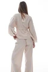 Blusa color crema con escote en V, mangas largas abullonadas y cintura ajustable con cordón.