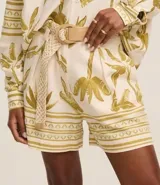 Short de cintura alta con estampado de cocoteros y elementos étnicos, trabillas en la cintura, cierre tradicional, pliegues y bolsillos falsos atrás. Incluye cinturón de rafia artificial con hebillas de argollas.