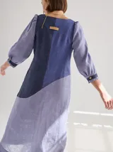 Vestido midi de lino color lila con escote en V y mangas 3/4 abullonadas con puño elástico. Presenta paneles laterales en denim y costuras a la vista en color rojo.