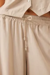 Pantalón palazzo color beige de lino, con cintura elástica y cordón ajustable.