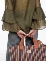 Camisa negra de lyocell y poliamida, con cuello clásico, mangas largas acampanadas con volados y cierre frontal con botones.